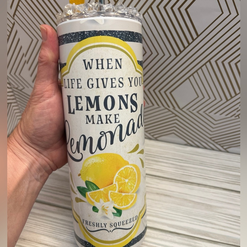 Stainless steel insulated tumbler with iced cubes top top and lemon accent.